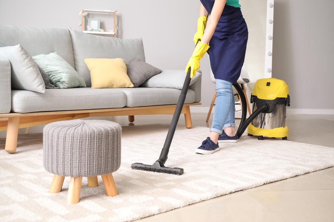 A Pristine cleaner vacuuming a bright living room